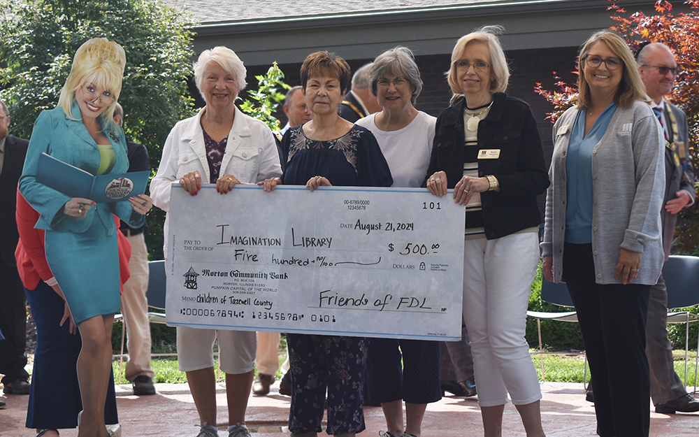 Friends members smiling holding a check donated to the Imagination Library from the Friends