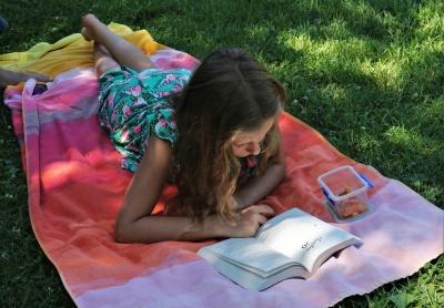 girl reading on a blanket in the grass