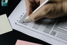 Hand holding a pencil and filling in bubbles on a test sheet