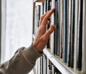 Person reaching for book on shelf