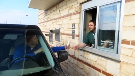 Library staff member handing a patron an item through the library's drive up service window