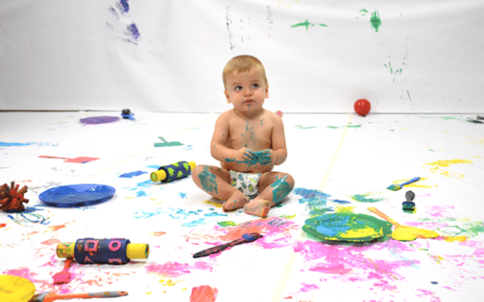 baby playing with paint on a white sheet