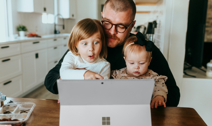 a man and two children view a computer